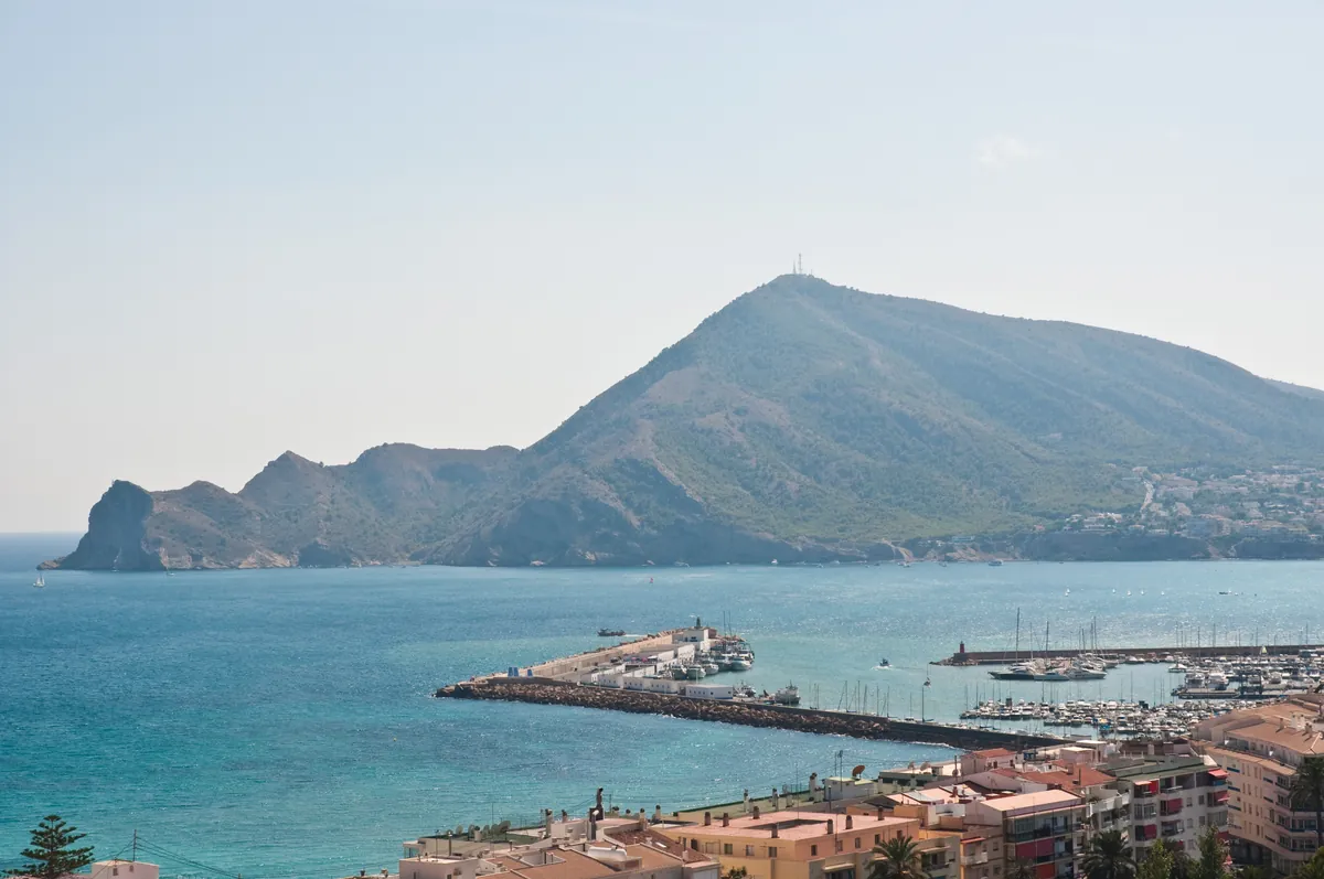 Aerial view of a Costa Blanca coastal town with a marina, mountains and Mediterranean sea