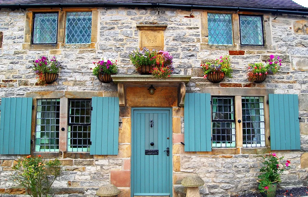 Charming stone holiday cottage with a front door and window flower boxes
