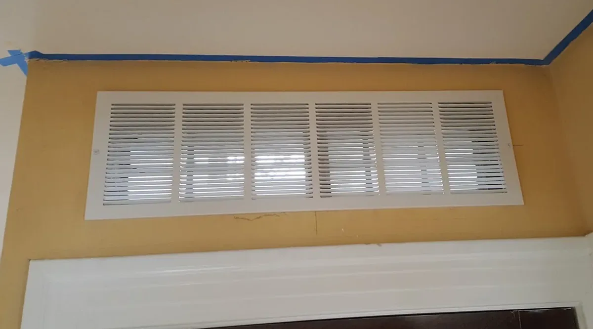 Rejilla de ventilación de un sistema de aire acondicionado por conductos en el techo de una vivienda